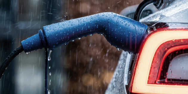 Rainwater beading on a blue charging connector locked into an electric car inlet