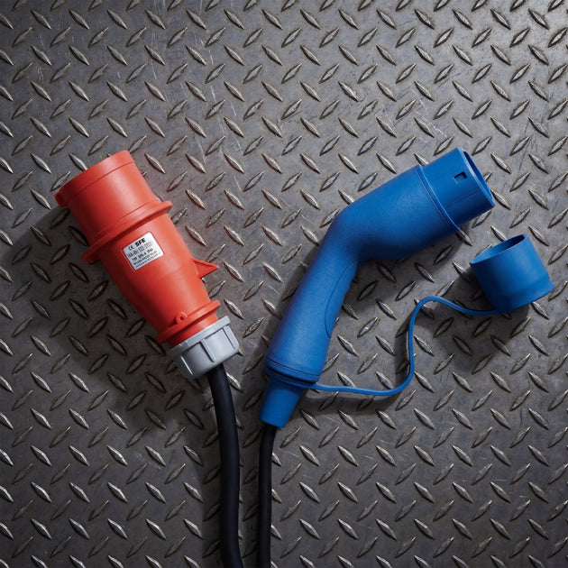 Red 400V CEE industrial plug and Type 2 connector on a steel checker plate